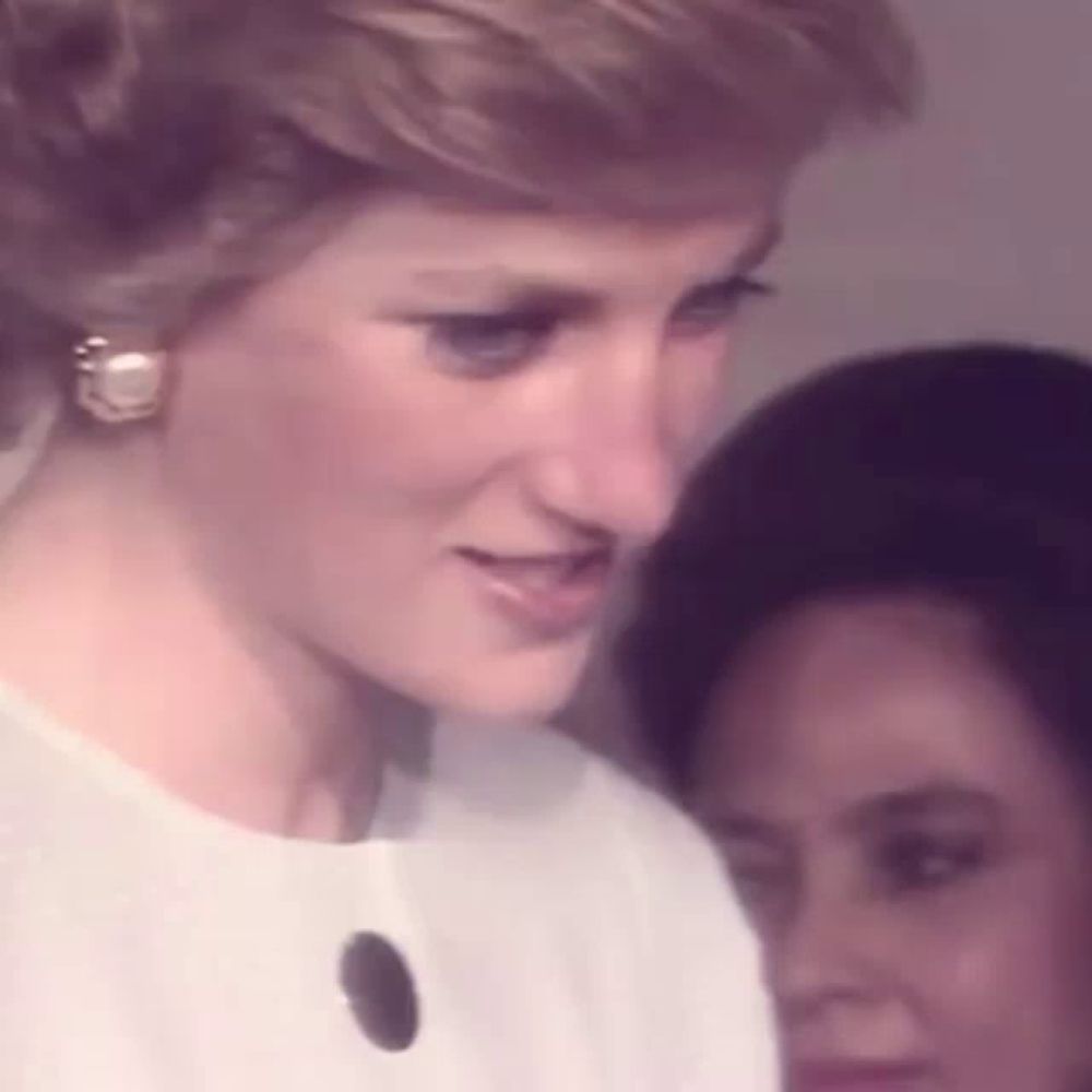 princess diana is wearing a white dress and earrings while standing next to a woman .