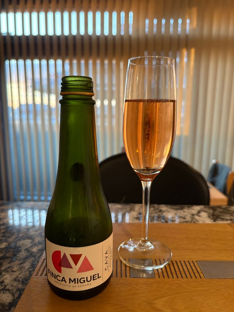 Small empty bottle and full glass of rosado cava