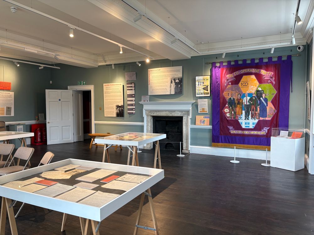 The exhibition- a room with lots of graphic panels and tabletop display cases with documents inside. And a large colourful banner