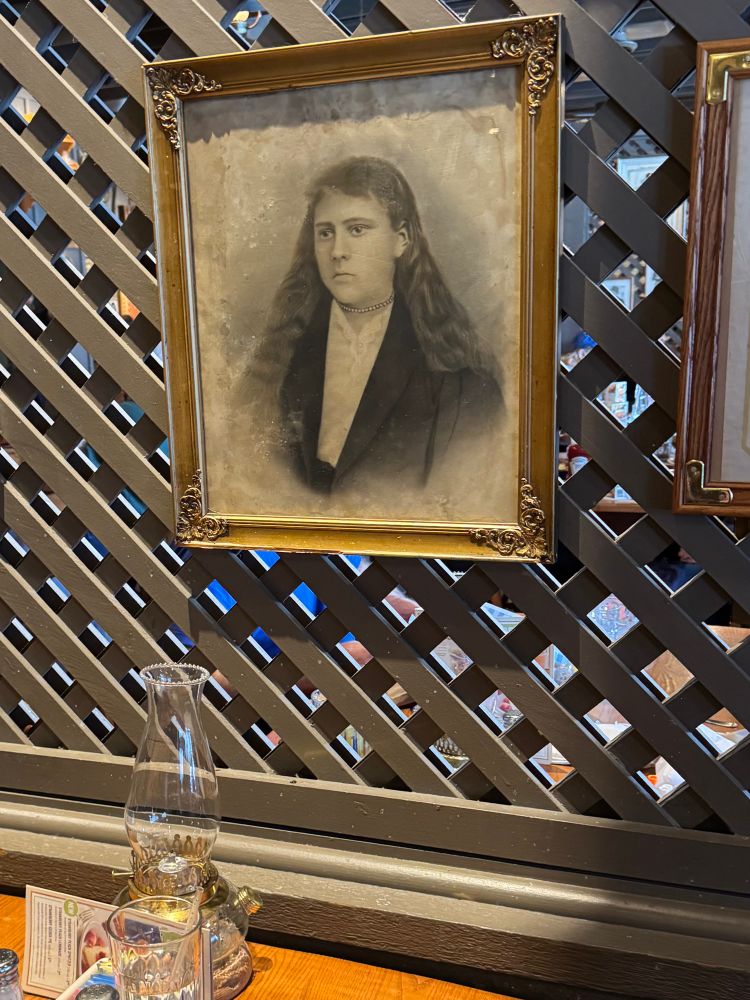 A framed antique photo that bears a haunting resemblance to Sarah Huckabee Sanders hangs on a wall over a table at a Cracker Barrel. 