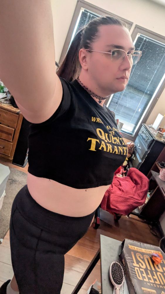 me posing in my room in a black crop top and bike shorts, my hair in a ponytail and a choker on my neck