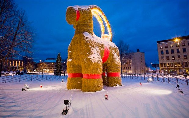 the gävle goat, a large goat made of straw and ribbon, standing in a snow-covered field