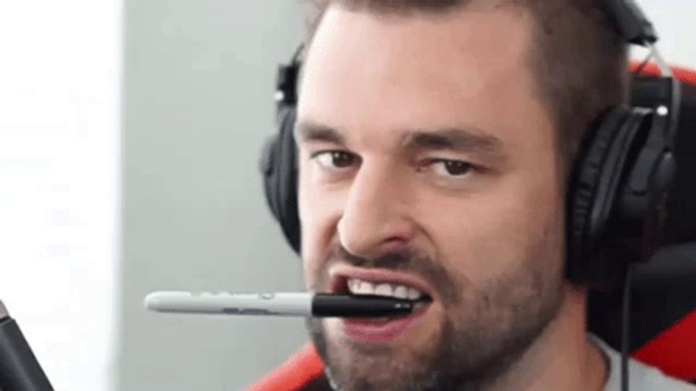 a man wearing headphones has a marker in his mouth .