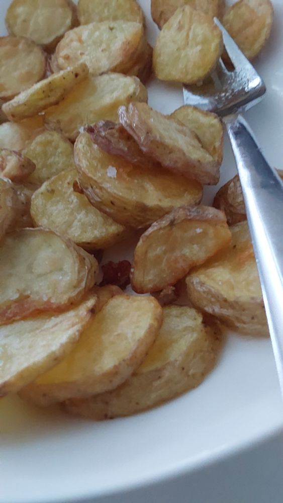 Kross fritierte Kartoffenscheiben auf einem weißen Porzellanteller, mit kristallinem Meersalz von Gran Canaria. 