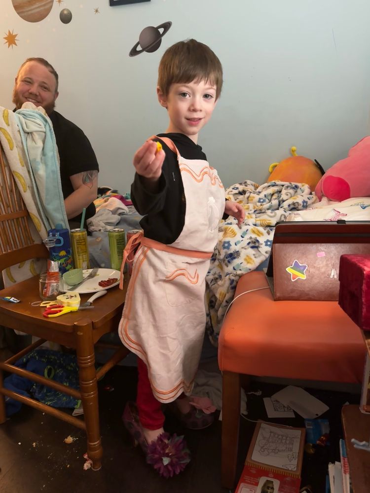 My toddler in heels, modeling the polar seltzer apron in his messy bedroom.