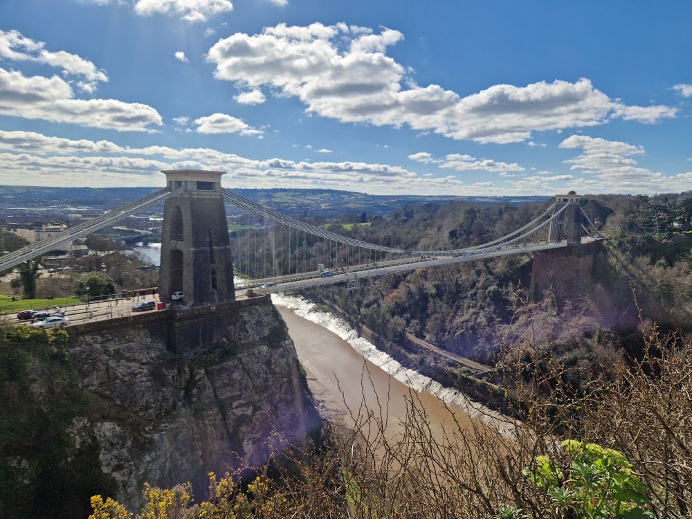 View of Clifton Suspension Bridge.  Sunshine, blue sky and clouds in the background