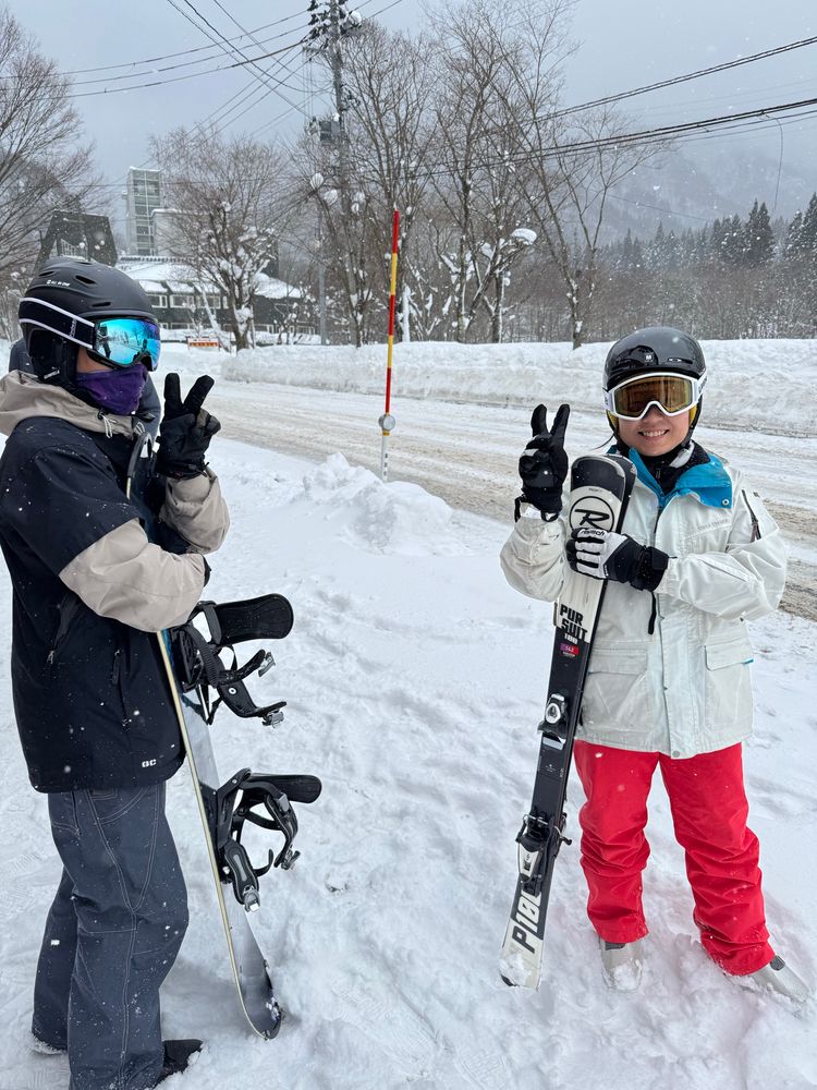 Two cool kids in the snow with their snowboard and ski gear.