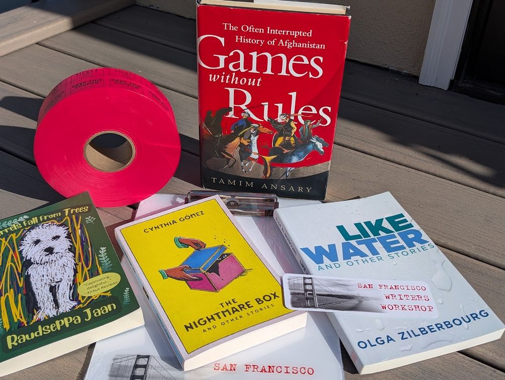 A group of books arranged next to a roll of raffle tickets atop a clipboard and with a bookmark