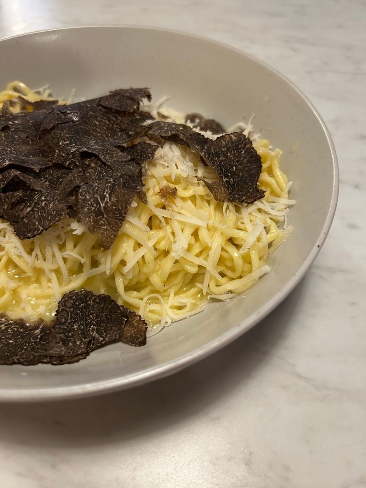 Buttery handmade pasta, thin and yellow, topped with shaved truffles and Parmesan