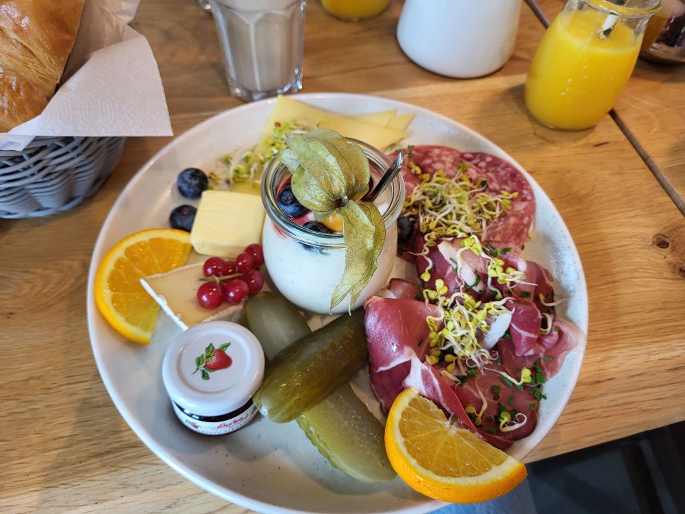 Teller mit lecker dekorierem Frühstück, z. B. Müsli, saure Gurke, Aufschnitt, Sprossen