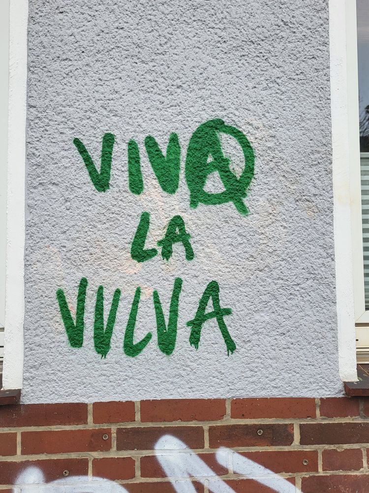 Grünes Graffito VIVA LA VULVA. Das A von Viva als Anarchie-A