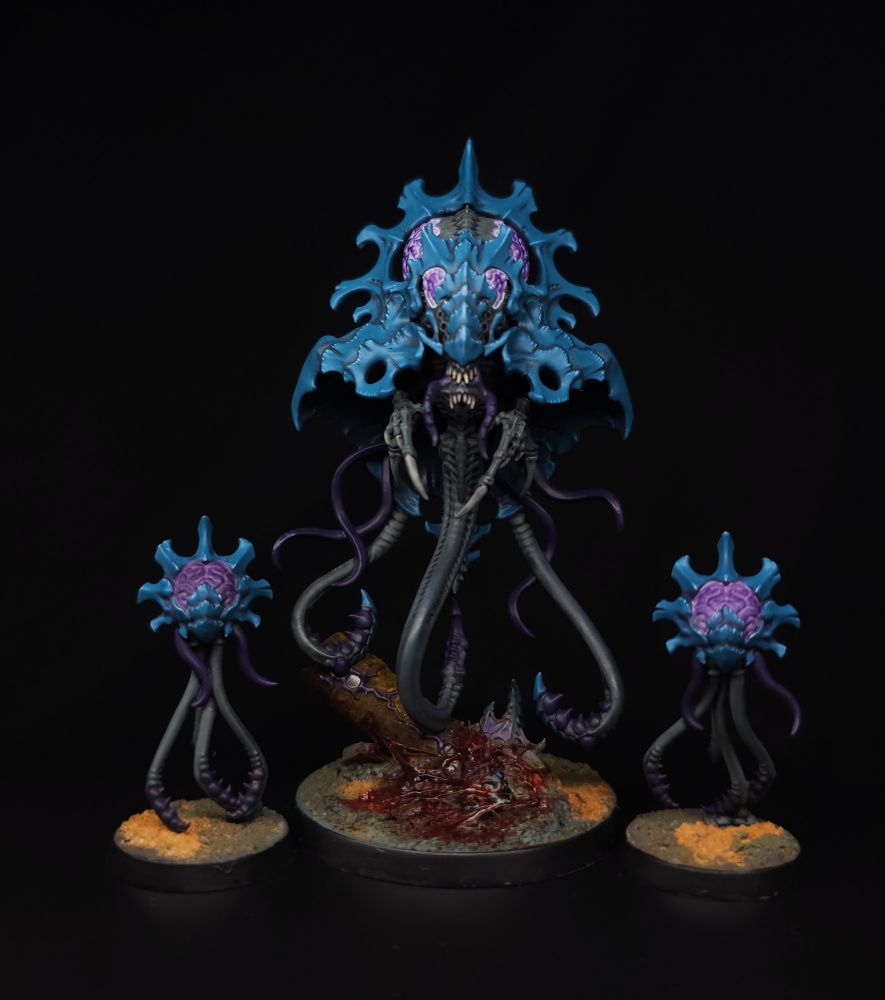 A floating brain with six limbs and a blue carapace is flanked by two smaller floating brains 