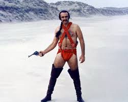Sean Connery on Zardoz wearing a red loin cloth with red bandoliers crossed over his chest and thigh boots 