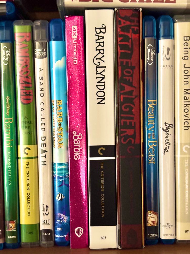 A row of blurays containing: Bambi, Bamboozled, A Band Called Death, Barb & Star Go To Vista Del Mar, Barbie, Barry Lyndon, The Battle of Algiers, Beauty and the Beast, Beginners, and Being John Malkovich