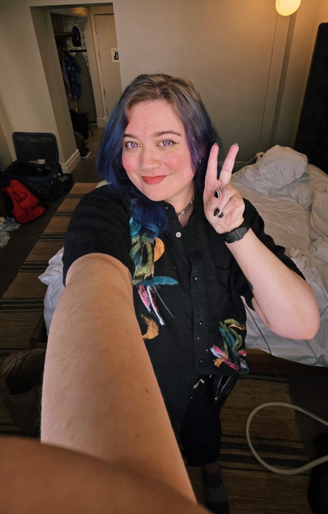 peace sign hotel selfie where my arm holding the camera looks hella long lol! black polo shirt with hawaiian print painted on, blue hair, purple contacts