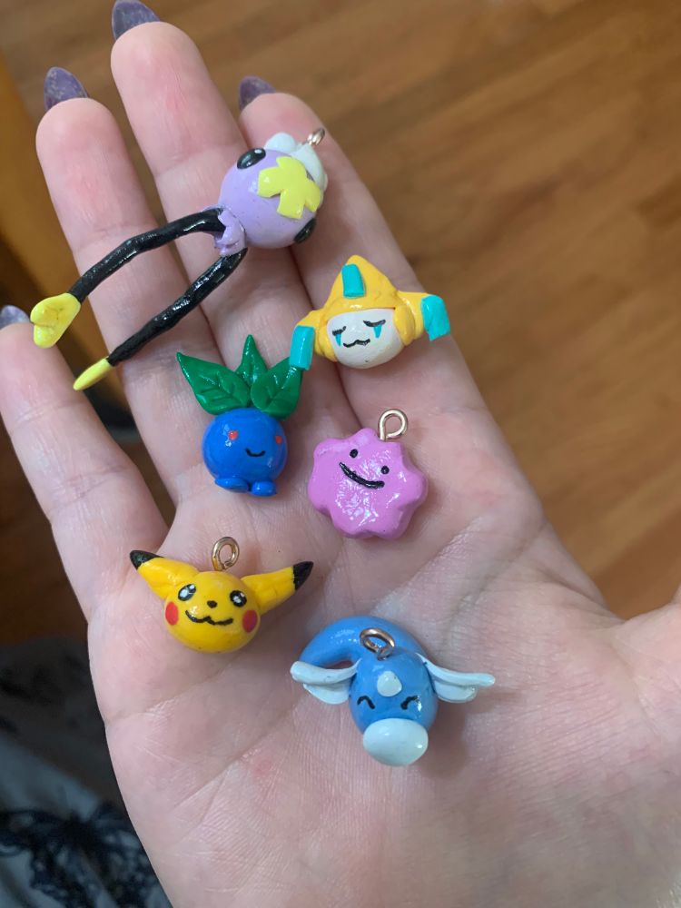 Handmade Pokémon clay charms by cosmicquarts. Pictured here are drifloon, Jirachi, oddish, ditto, Pikachu, and dratini!