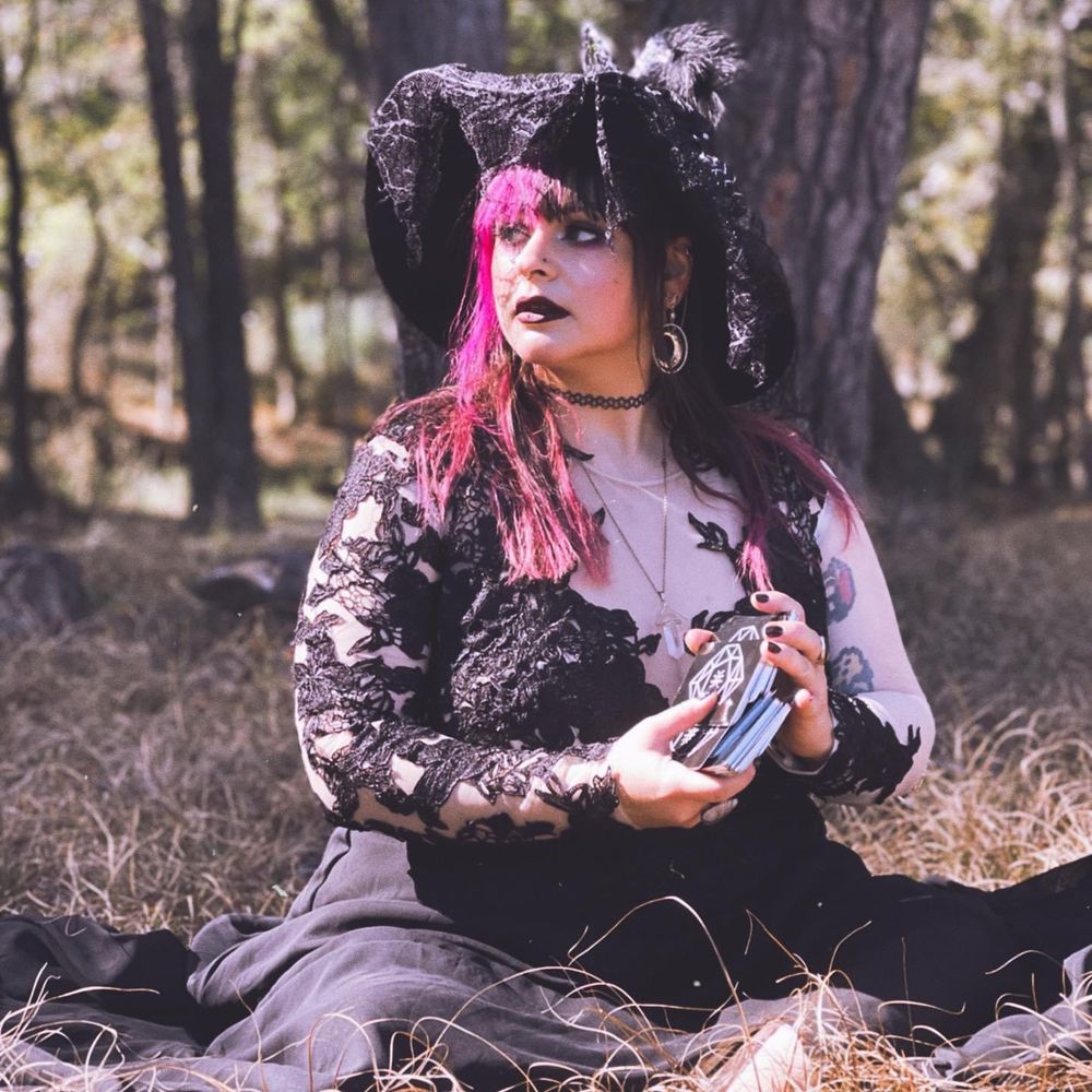Quartsy dressed as a witch while shuffling a tarot deck in the woods 