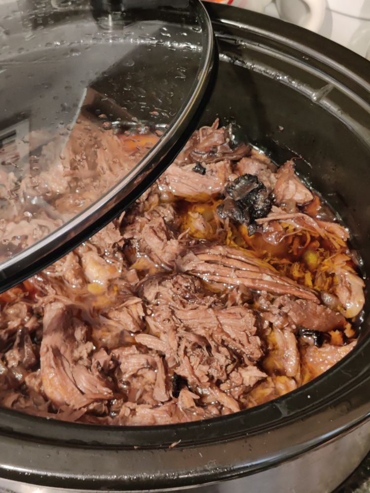 Shredded pork in a black and silver Crock pot with the lid moved to the side so you can look inside. With the shredded/pulled pork is mushrooms, onions, and barbecue sauce. It's about 5lbs of pork.