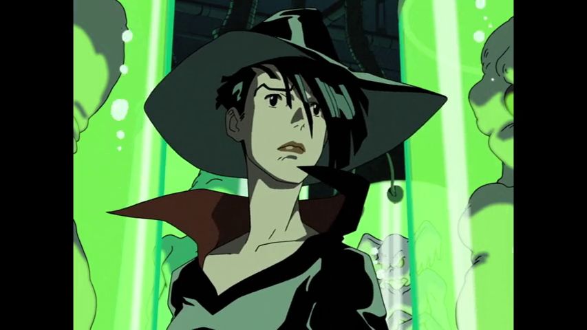 A woman in a black leather costume and wide brimmed fedora stands in front of a display full of bright green glass tubes with alien life forms floating inside them. She looks deeply concerned, but ready to fight.