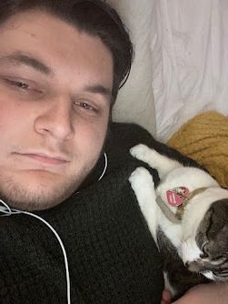 On the left is Niall, in a black jumper. On the right is his cat, Princess resting on his shoulder