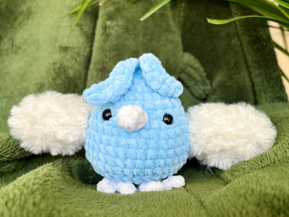 Une peluche en crochet de Tylton, un poussin bleu avec des ailes nuages 