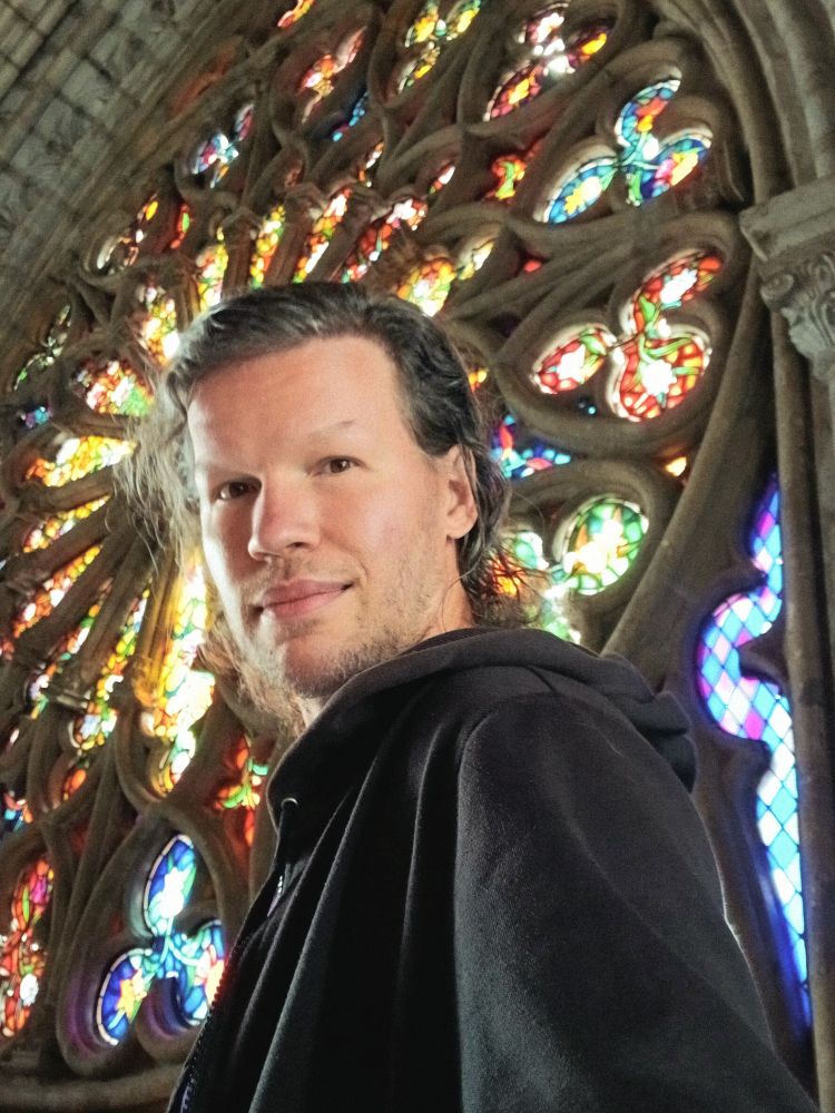 Me taking a selfie in frony of the gigantic round stained-glass window.