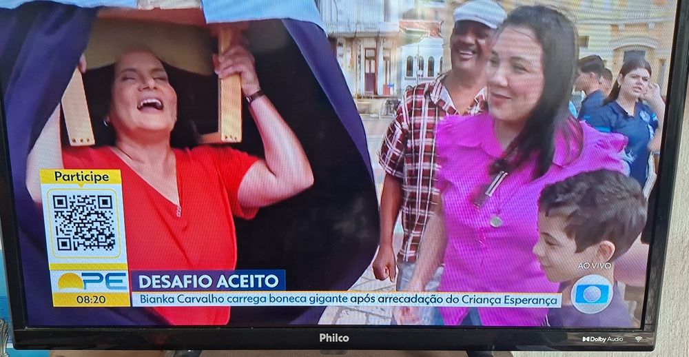 A repórter do Bom Dia Pernambuco, Bianka Carvalho, carregando um boneco de Olinda inspirado nela pelo desafio do Criança Esperança 