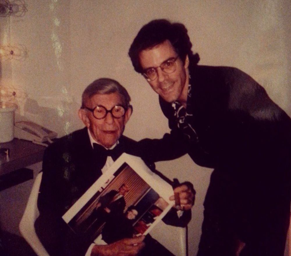 A man in a photo with George Burns who is holding a photo of the same man with a wax figure of George Burns