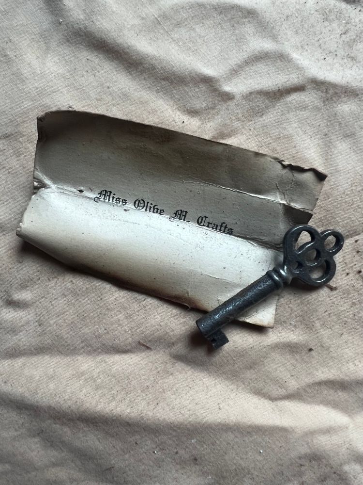 A skeleton key and a card that says “Miss Olive M. Crafts”