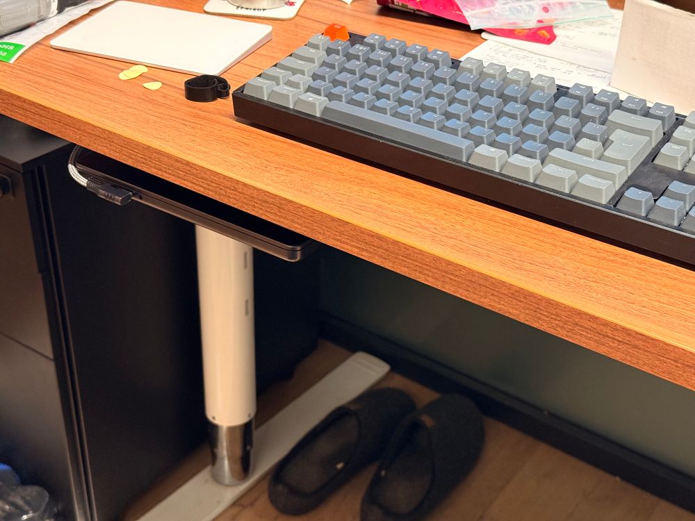 MacBook suspended under a cherry walnut desk