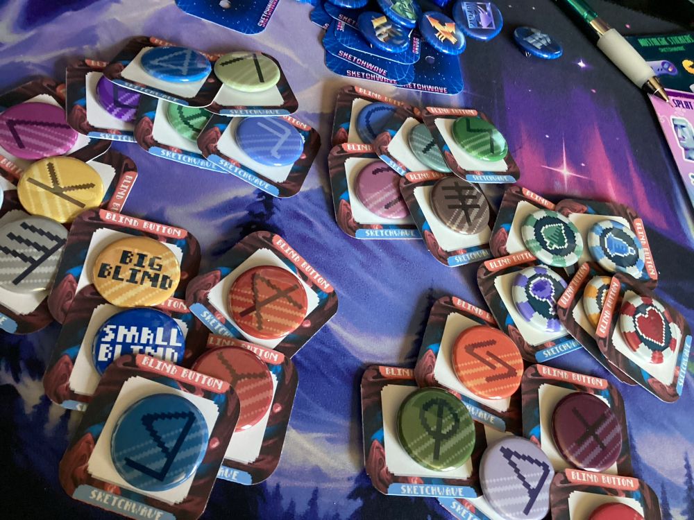 An image of the several blinds from the game Balatro in the form of pinback buttons! They’re available for purchase at https://sketchwave.bigcartel.com