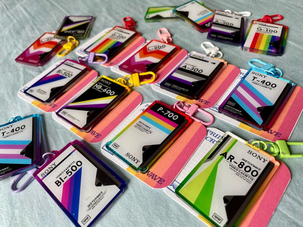 an image of sketchwave’s pride vhs tape charms, restocked and available tomorrow at 12p est!