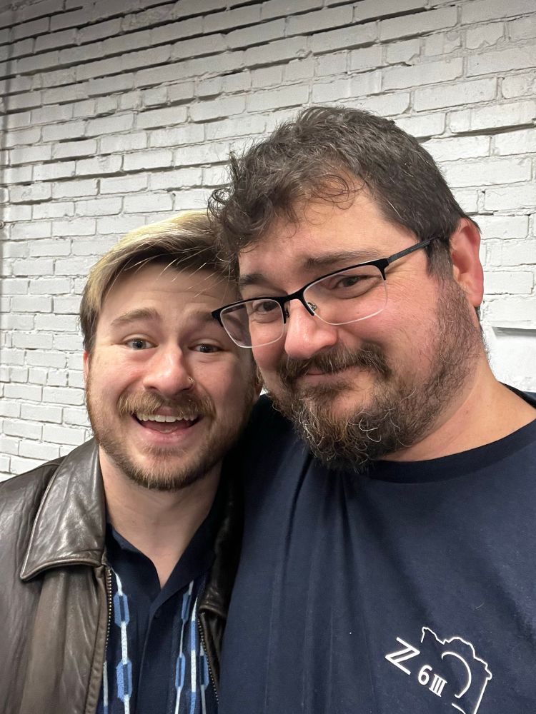 Two men in a side hug, smiling.