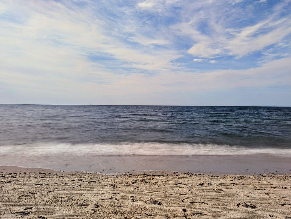 A gentle beach with gentle waves and whispy clouds