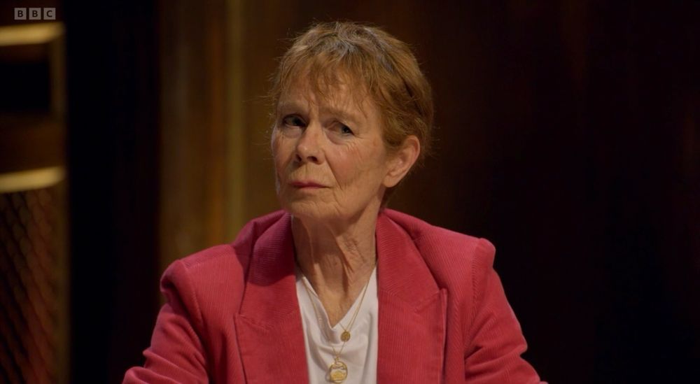 Celia Imrie, British actress and Celebrity Traitors contestant, sitting at the round table and looking to the left with a frown and a skeptical expression of disbelief or worry