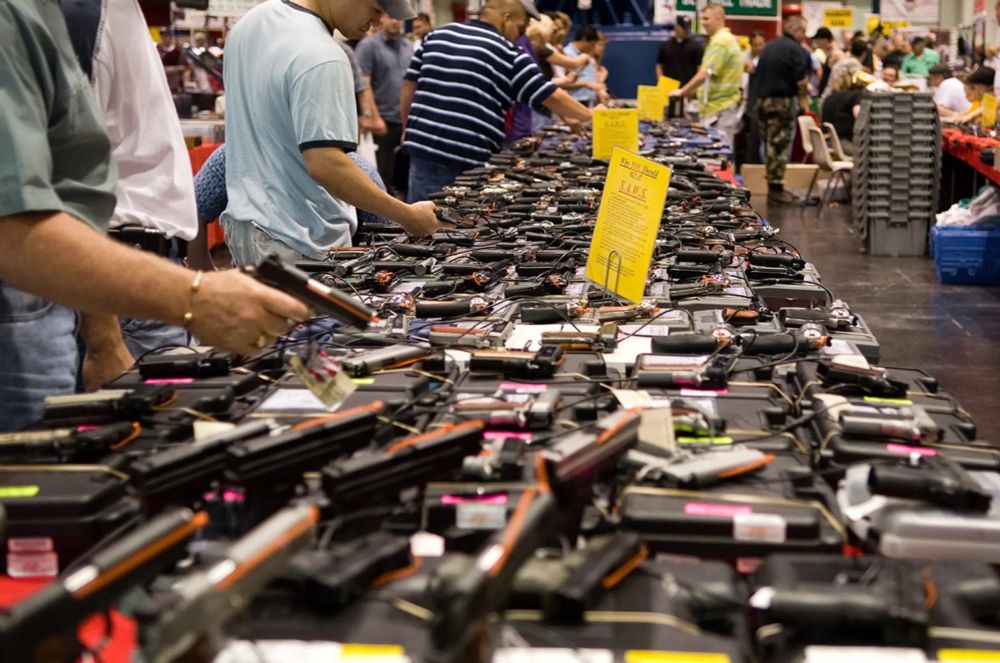 Men observing pistols at a gun show.