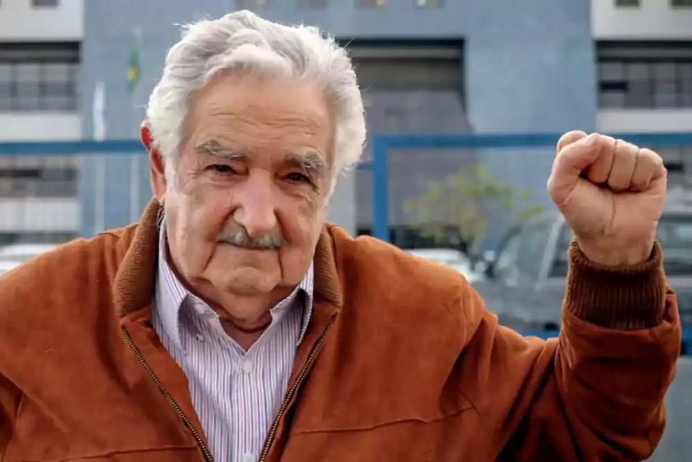 Pepe Mujica with his left hand raised in a solidarity fist.