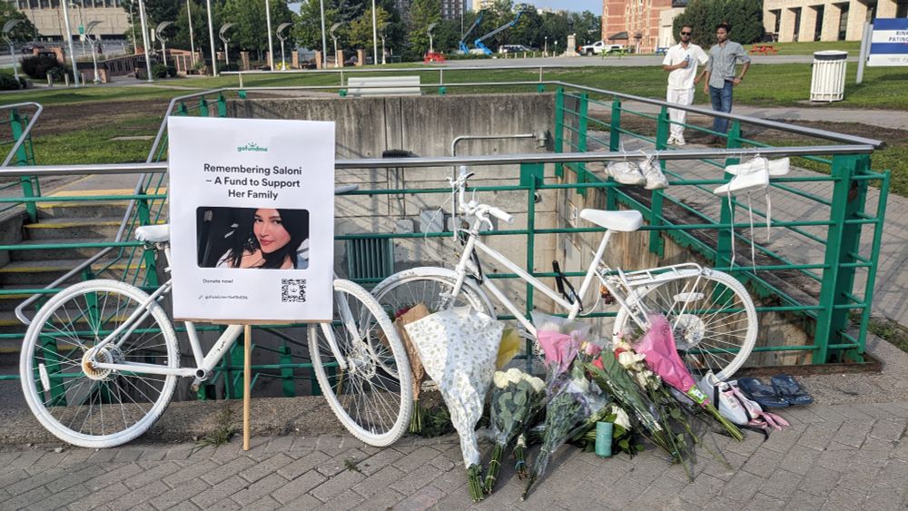 A vigil with ghost bikes, ghost shoes, flowers and a go fund me sign