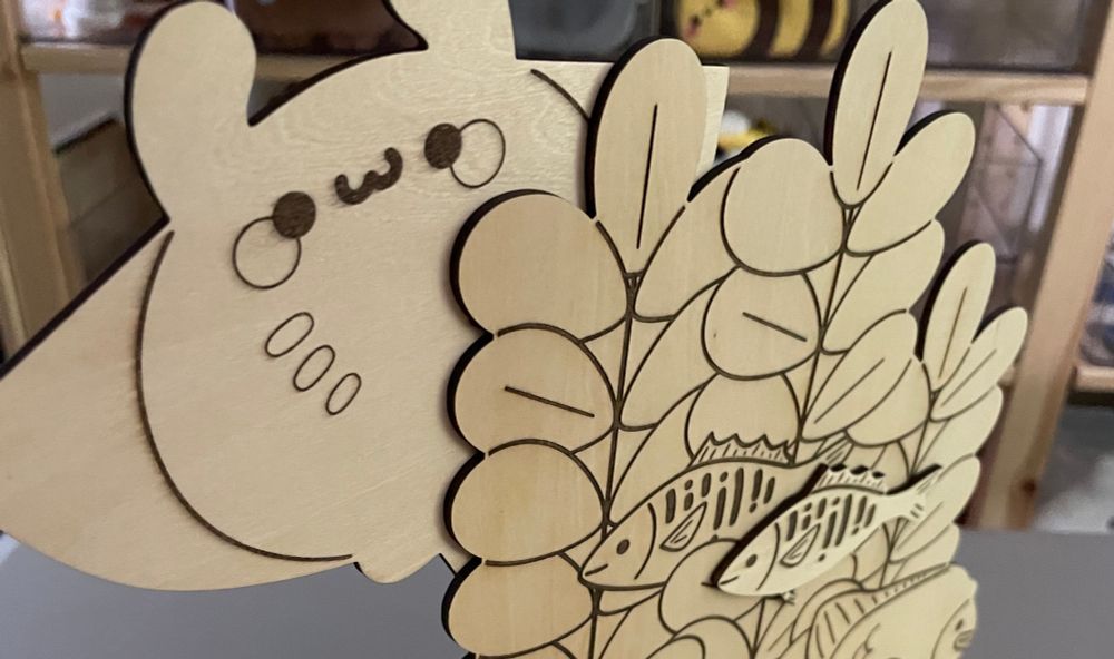 Photograph of wood cut illustration featuring a manta ray, kelp and some fish. 