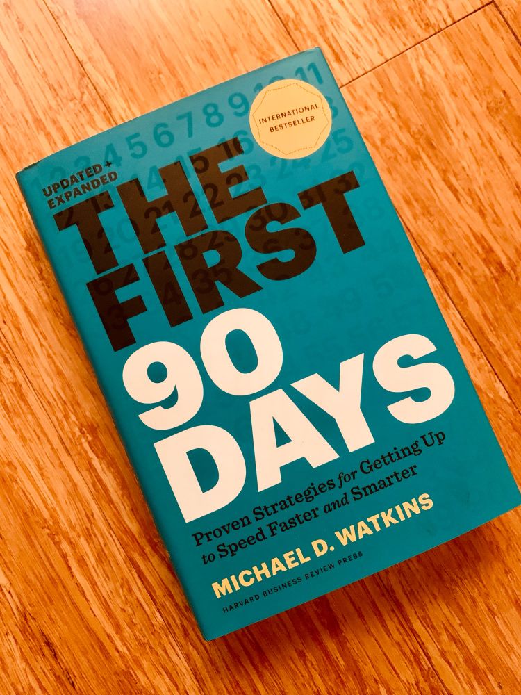 The book “The First 90 Days” laying on a wooden surface. 