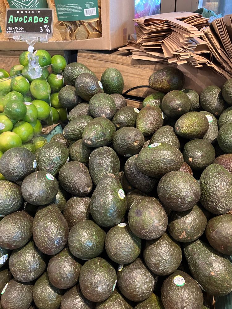 A photo of avocado and just a few limes at store shelf