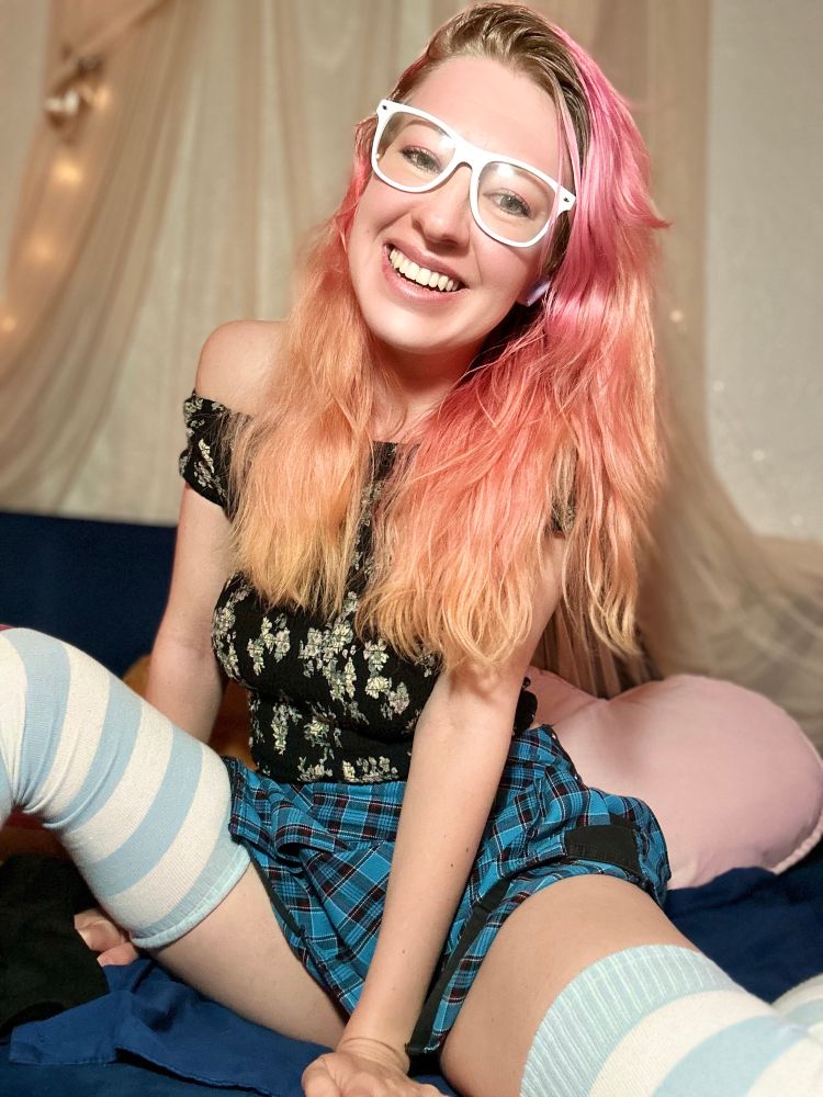 Valentine smiling on her couch wearing glasses and thigh high stockings 