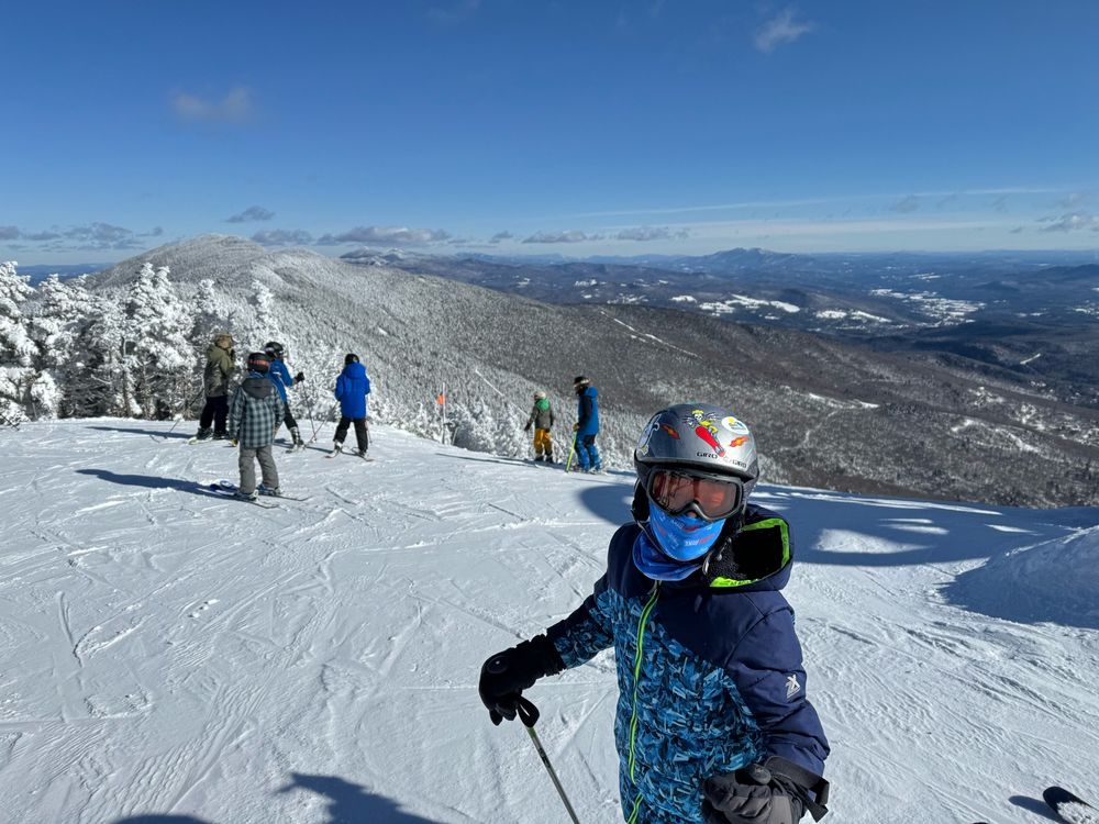 10-year-old about to ski down a double black diamond at Sugarbush in Vermont. Lots of snow and mountain views. 