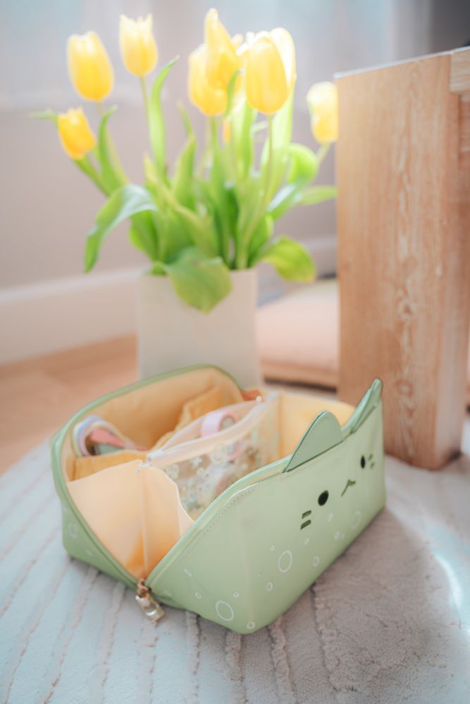 the green cat makeup bag but unzipped with its light yellow interior showing