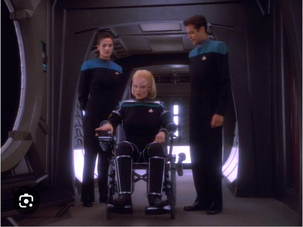 Still from the Star Trek: Deep Space Nine episode “Melora” where the titular character is in a wheelchair accompanied by Jadzia Dax and Julian Bashir