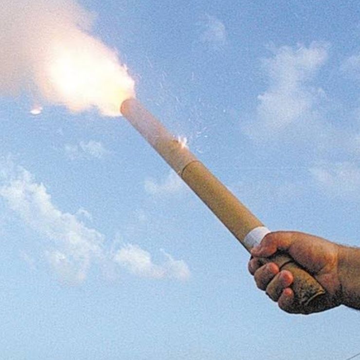 A imagem retrata uma mão segurando um fogo de artifício aceso prestes a ser lançado
