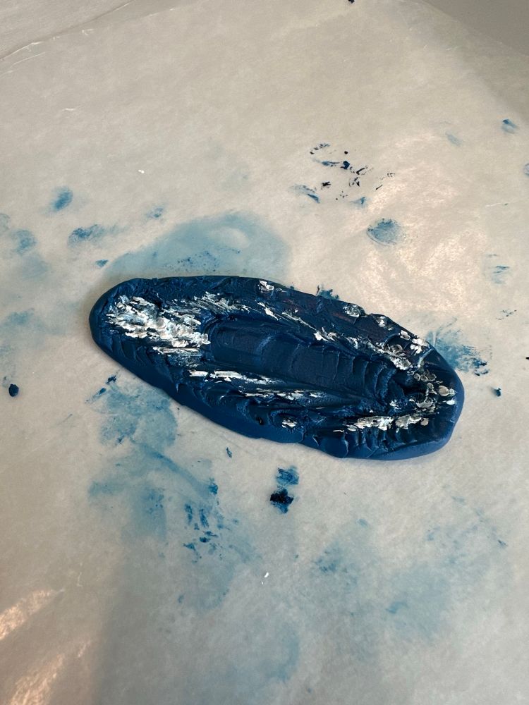 A test batch of plumbers putty and blue oil paint mixed to look like ocean water. White oil paint was used to simulate a wake. 

Satisfied with the result, I will eventually make a larger batch and get it into a bottle for a ship-in-bottle project. 