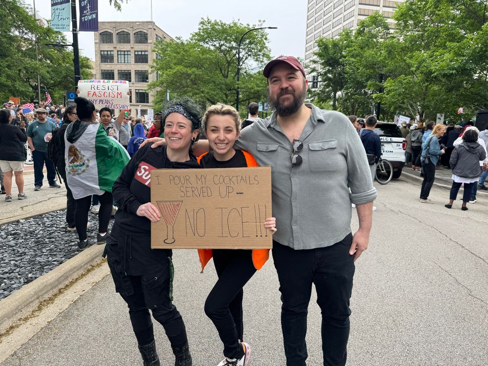 I’m standing between two people holding one of their protest signs which reads, “I POUR MY COCKTAILS SERVED UP — NO ICE!!!”