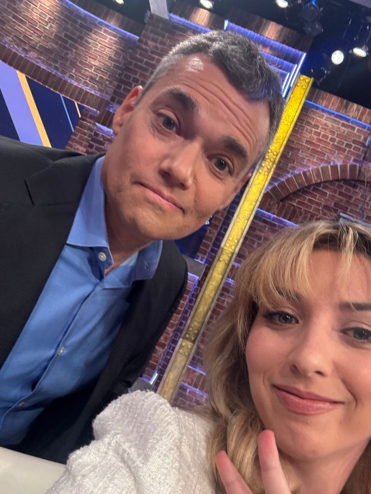 Me and Peter on the set of CNN’s News Night with Abby Phillip. Peter is wearing a blue button-down shirt and black suit jacket. I’m wearing a white romper and flashing a peace sign.