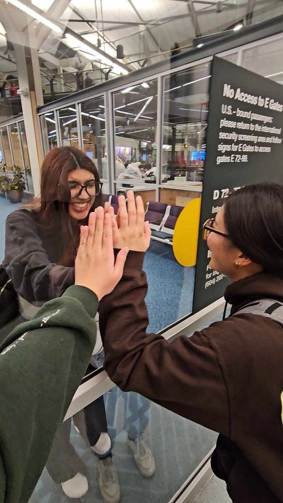 me, brianna, and Jazzy at the airport. Me and Brianna are on one side of a window while Jazzy is on the other side. We all have our hands against the window as if trying to touch. 